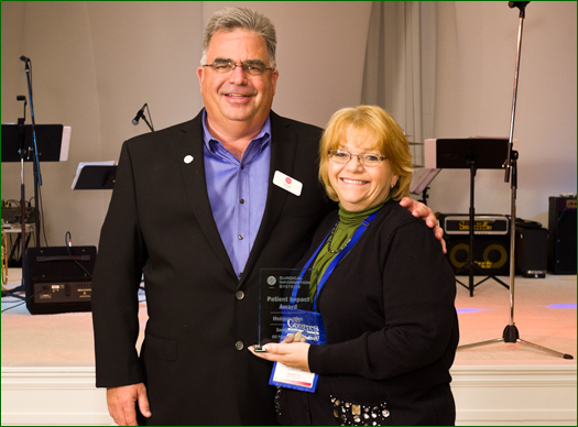 On behalf of Medcenter One, Sandy Fleck accepts the Patient Impact Award from Ed Daihl, CEO of Surgical Information Systems (SIS). The Patient Impact Award is one of a number of Perioperative Leadership Awards SIS presents at its annual user conference.